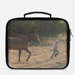 Jonge kleine cowgirl met een roze westernhoed trekt haar paard aan de leiband, foto op Lunch Box Tote Bag