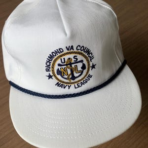 May include: White baseball cap with a navy blue rope detail and a curved brim. The cap features an embroidered emblem with the text "RICHMOND VA COUNCIL NAVY LEAGUE" and the letters "US N L" in a circular design.