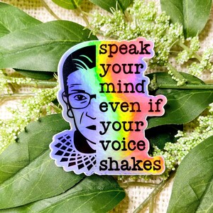 Può includere: Un adesivo olografico arcobaleno con un ritratto di Ruth Bader Ginsburg e il testo "speak your mind even if your voice shakes".