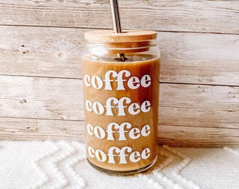 May include: A glass coffee tumbler with a bamboo lid and a stainless steel straw. The tumbler has the word "coffee" written on it five times in a retro font.
