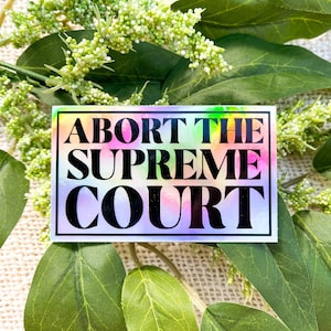 Puede incluir: Una pegatina con fondo arcoíris y texto negro que dice "Abort the Supreme Court".