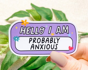 May include: A sticker with a purple name tag design. The text reads "HELLO I AM PROBABLY ANXIOUS" in white and black. The sticker is decorated with small flowers and a heart.
