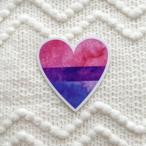 May include: A watercolor heart sticker with a pink, purple, and blue color scheme representing the bisexual pride flag.