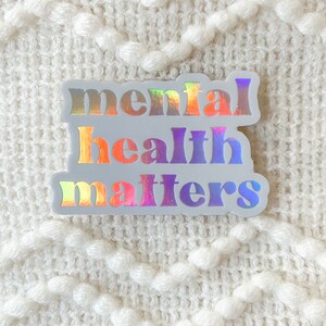 May include: A white sticker with the text "mental health matters" in rainbow iridescent letters.