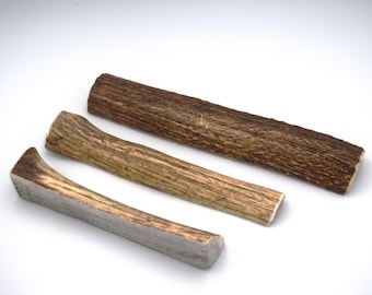 May include: Three different sizes of natural antler dog chews. The chews are light brown with a rough texture.