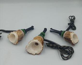 May include: A collection of hunting calls. Each call features a natural antler body, a black mouthpiece, and a green accent. A black and green cord is attached to each call.