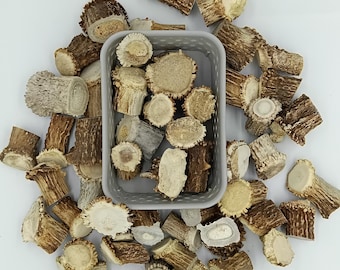 May include: A collection of brown and white deer antler pieces in a gray container. The antler pieces are various shapes and sizes.