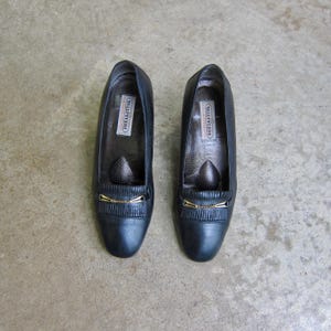 May include: A pair of black leather shoes with gold buckles and the word "Willaert" printed on the inside of each shoe.