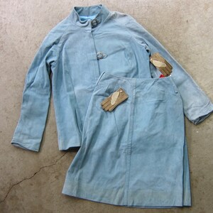 May include: A light blue suede jacket and skirt set with two pairs of brown leather gloves.
