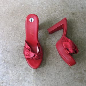 Peut inclure: Une paire de sandales à talons en satin rouge avec un détail de nœud. Les sandales sont de taille 8.
