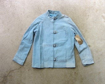 Peut inclure: Une veste bleu clair avec un col mandarin et quatre boutons argentés. La veste a des manches longues et une silhouette légèrement cintrée.