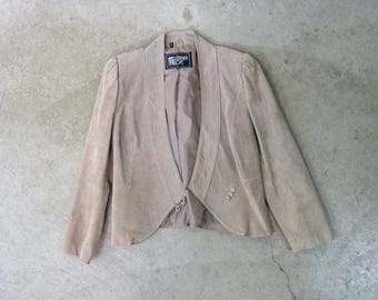 Könnte beinhalten: Eine hellbraune Wildlederjacke mit spitzem Kragen und einem einzigen Knopfverschluss. Die Jacke hat ein Etikett mit der Aufschrift "Leather Loft".