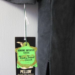 Peut inclure: Une &eacute;tiquette verte avec le texte "Genuine Imported Suede Town and Travel Casuals" et les num&eacute;ros "9" et "10" de chaque c&ocirc;t&eacute;. L'&eacute;tiquette est attach&eacute;e &agrave; une jupe en daim noir avec une fente dans le dos. L'&eacute;tiquette porte &eacute;galement le texte "Pellon shapes the fashion" en bas.