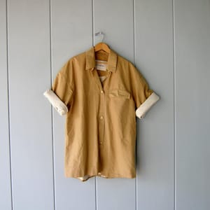 May include: A set of three ceramic mugs with a speckled, matte finish. The mugs are in shades of cream, light gray, and dark gray. Each mug has a simple, minimalist design and a rounded handle. The mugs are stacked on top of each other.