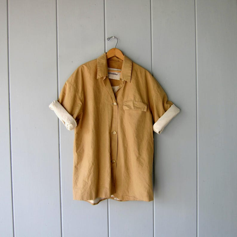 May include: A set of three ceramic mugs with a speckled, matte finish. The mugs are in shades of cream, light gray, and dark gray. Each mug has a simple, minimalist design and a rounded handle. The mugs are stacked on top of each other.