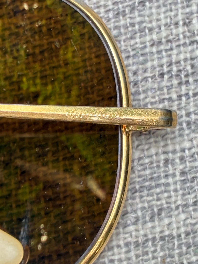 Puede incluir: Primer plano de gafas de sol con montura dorada y lentes marrones. La montura es de estilo aviador cl&aacute;sico, con una fina montura de metal dorado. Las lentes son de color marr&oacute;n oscuro, y el aspecto general es vintage y elegante.