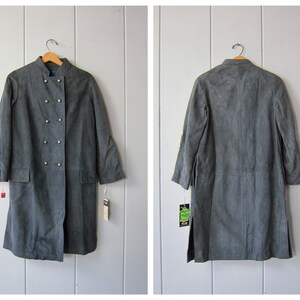 Peut inclure: Un long manteau en daim gris avec une fermeture &agrave; double boutonnage et des d&eacute;tails boutonn&eacute;s. Le manteau a un col mandarin et des manches longues.