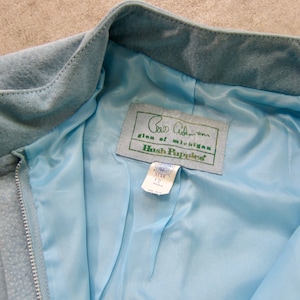 May include: A light blue suede jacket with a zip fastening and a Hush Puppies label. The label reads "Glen of Michigan Hush Puppies".