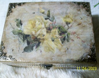 May include: A decorative wooden box with a vintage floral design featuring yellow roses and green leaves. The box has a gold-colored metal trim and a beaded border around the edge. The box is closed and the date 11/04/2023 is visible in the bottom right corner.