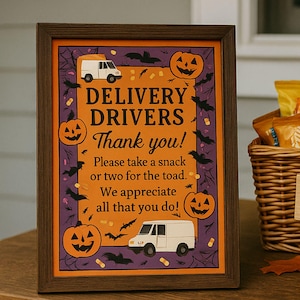 Könnte beinhalten: Ein gerahmtes Halloween-Schild mit dem Text "Delivery Drivers Thank you!" und einem Korb mit Snacks. Das Schild ist 20x25 cm groß und zeigt Kürbisse, Fledermäuse und Lieferwagen. Ein Korb mit Snacks und Wasserflaschen steht neben dem Schild.