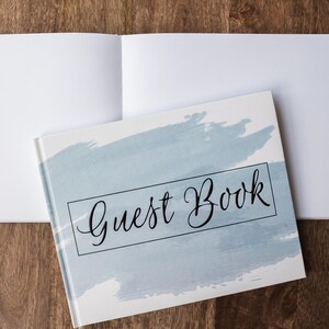 May include: A white guest book with a blue watercolor design and the text "Guest Book" in black lettering.