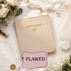 May include: A beige, square-bound book with gold-colored metal corner protectors. The word "OFFICIANT" is printed in gold lettering on the front cover, accompanied by a small gold leaf icon. The book is surrounded by white flowers and ribbons.