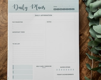 May include: A spiral-bound daily planner pad with a light blue header featuring the text Daily Plans. The page includes sections for daily affirmation, top priorities, important times, a to-do list, notes, meal tracking, self-care, exercise, water intake, and today's achievements.
