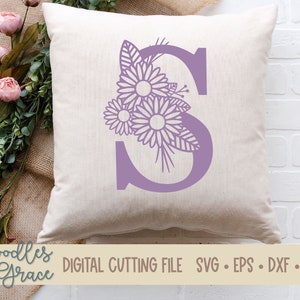 May include: A purple letter S with a floral design. The flowers are stylized and have a delicate, intricate design. The letter is on a white background.