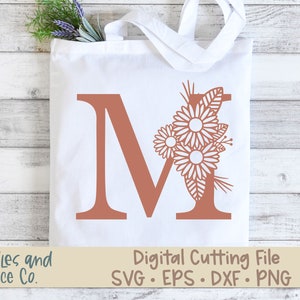 May include: A digital cutting file featuring the letter M with a floral design. The letter is a terracotta color and the flowers are white. The text "Digital Cutting File SVG. EPS. DXF. PNG" is at the bottom of the image.