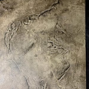 Puede incluir: Una pieza de arte mural rectangular con una superficie texturizada similar a la piedra en tonos beige, gris y marrón. La superficie presenta grietas y fisuras profundas e irregulares que crean un aspecto rugoso y desigual, enmarcada por un borde negro fino.