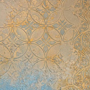 Pode incluir: Uma superfície texturizada com um padrão geométrico repetitivo de círculos entrelaçados e formas florais de quatro pétalas em azul suave e ouro envelhecido. O acabamento parece desgastado com uma consistência rugosa semelhante a gesso.