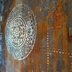 May include: Close-up of a textured wall with a distressed, aged appearance. The design features large, ornate circular patterns in silver against a backdrop of rusty brown and grey tones. The overall aesthetic is vintage and industrial.