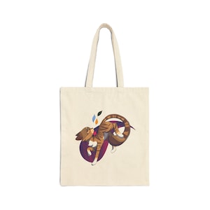 May include: Cream-colored tote bag featuring a cartoon cat design. The cat is brown with tiger stripes, curled around a purple shape. The design includes colorful leaf accents. The bag has two long handles.