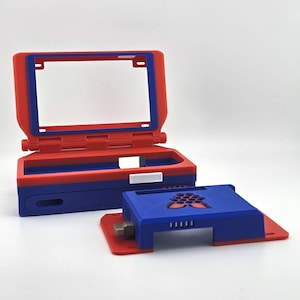 May include: A red and blue plastic computer case with a hinged screen frame and a separate base component. The base features a Raspberry Pi logo cutout on the top surface, ventilation slots, and a small metallic switch on the side panel.