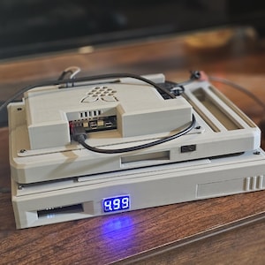 May include: A white, rectangular, multi-layered device with a blue digital display showing the number 489. The device has a black cable attached to it.