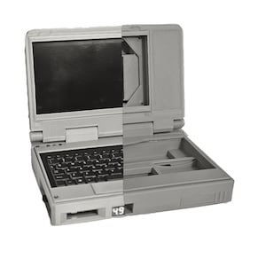 May include: A gray laptop computer with a black keyboard and a blank screen. The laptop is open and the lid is slightly ajar. The laptop has a number "49" printed on the bottom right corner.