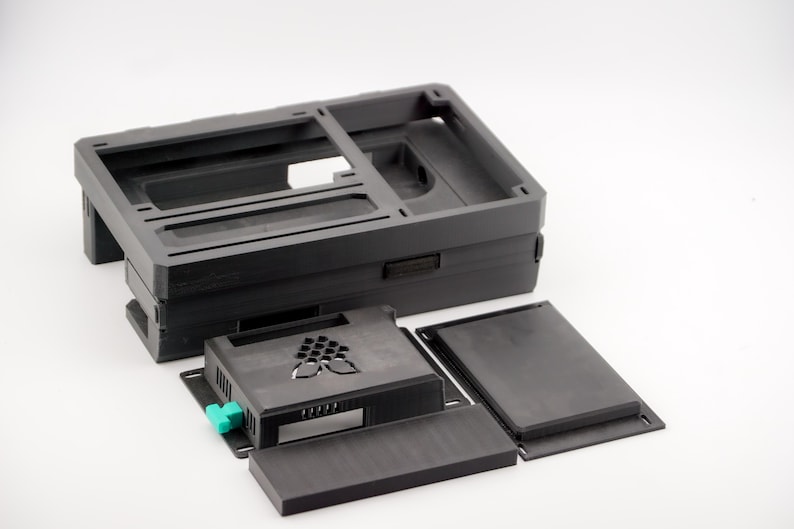 May include: A black plastic case for a Raspberry Pi computer. The case is made up of several pieces that fit together. The case has a logo on the front that says "Raspberry Pi".