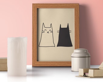 Peut inclure: Une impression encadrée avec une illustration en noir et blanc de deux chats. L'impression est sur un fond rose clair et repose sur une surface blanche avec une bougie, une boîte et un petit récipient en étain.