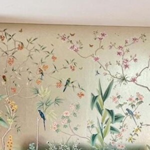 May include: A detailed mural featuring a botanical design with birds, flowers, and foliage. The color palette includes soft greens, pinks, and golds, creating a serene and elegant aesthetic. The artwork is applied to the walls of a room.