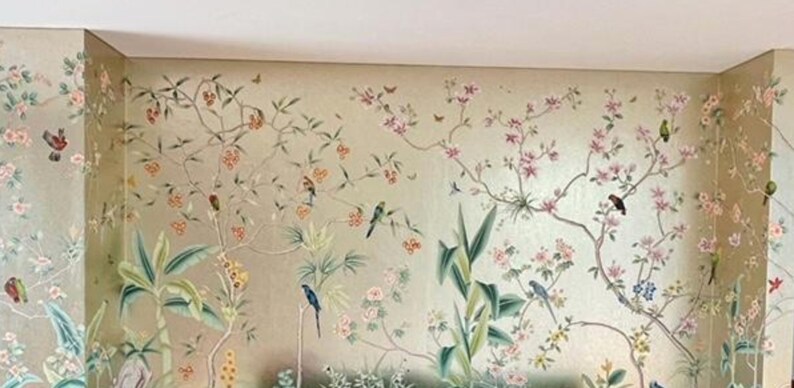 May include: A detailed mural featuring a botanical design with birds, flowers, and foliage. The color palette includes soft greens, pinks, and golds, creating a serene and elegant aesthetic. The artwork is applied to the walls of a room.
