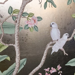 May include: A decorative panel featuring a botanical design with two white parrots perched on a tree branch. The artwork includes pink flowers, green leaves, and a gold and dark background, creating a tropical theme.