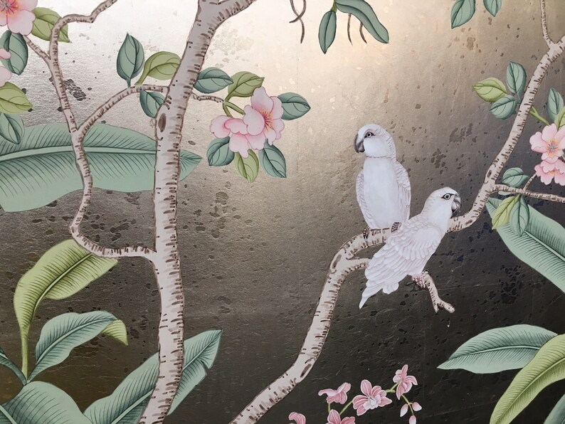 May include: A decorative panel featuring a botanical design with two white parrots perched on a tree branch. The artwork includes pink flowers, green leaves, and a gold and dark background, creating a tropical theme.