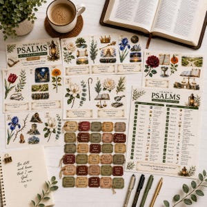 May include: A collection of printed paper sheets featuring The Book of Psalms 150-day reading plan, illustrated with botanical drawings, crowns, and landscapes. Includes small rectangular tags with text, a spiral-bound notebook with the quote Be still and know that I am God, and four pens.