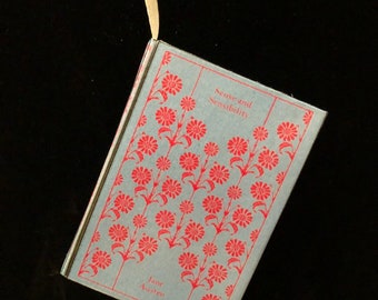 May include: A blue book with a red floral pattern and the title "Sense and Sensibility" by Jane Austen.