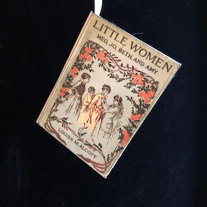 May include: A vintage book cover for "Little Women" by Louisa M. Alcott. The cover features an illustration of four girls in a garden setting with a floral border.