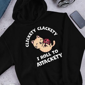 May include: Black hooded sweatshirt with a white graphic of a cat holding a red dice. The text on the graphic reads "Clickety Clackety I Roll To Attackety".