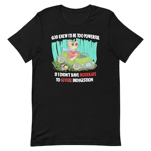 Puede incluir: Camiseta negra con un gato de dibujos animados conduciendo un coche. El texto de la camiseta dice "Dios sabía que sería demasiado poderoso si no tuviera indigestión moderada a severa."