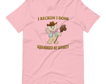以下が含まれることがあります： ピンクのTシャツに、カウボーイハットをかぶって木の馬を持った漫画のテディベアが描かれています。Tシャツには「I reckon I done squandered my divinity」という文字が印刷されています。