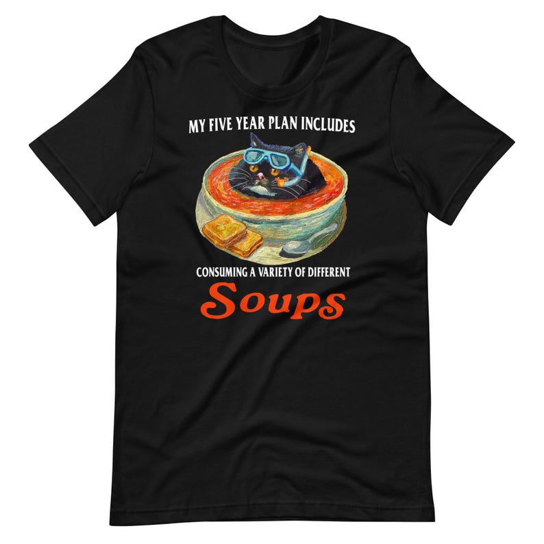 May include: Black t-shirt with a graphic of a black cat wearing blue goggles in a bowl of soup. The text reads "MY FIVE YEAR PLAN INCLUDES CONSUMING A VARIETY OF DIFFERENT SOUPS."