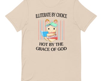 May include: Beige t-shirt featuring a cartoon bunny wearing a book on its head and holding a book. The text on the shirt reads "ILLITERATE BY CHOICE HOT BY THE GRACE OF GOD".